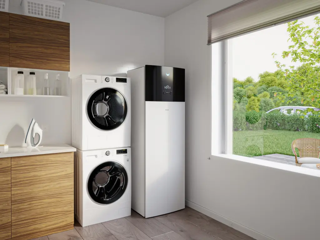 Unité intérieure au sol Daikin Altherma 3 H HT, colonne blanche à façade noire, à côté d’un lave-linge dans une buanderie claire