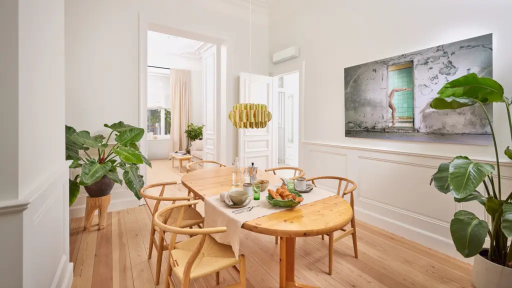 Climatiseur mural Daikin Perfera blanc au-dessus d’une table en bois, dans une salle à manger claire avec des plantes