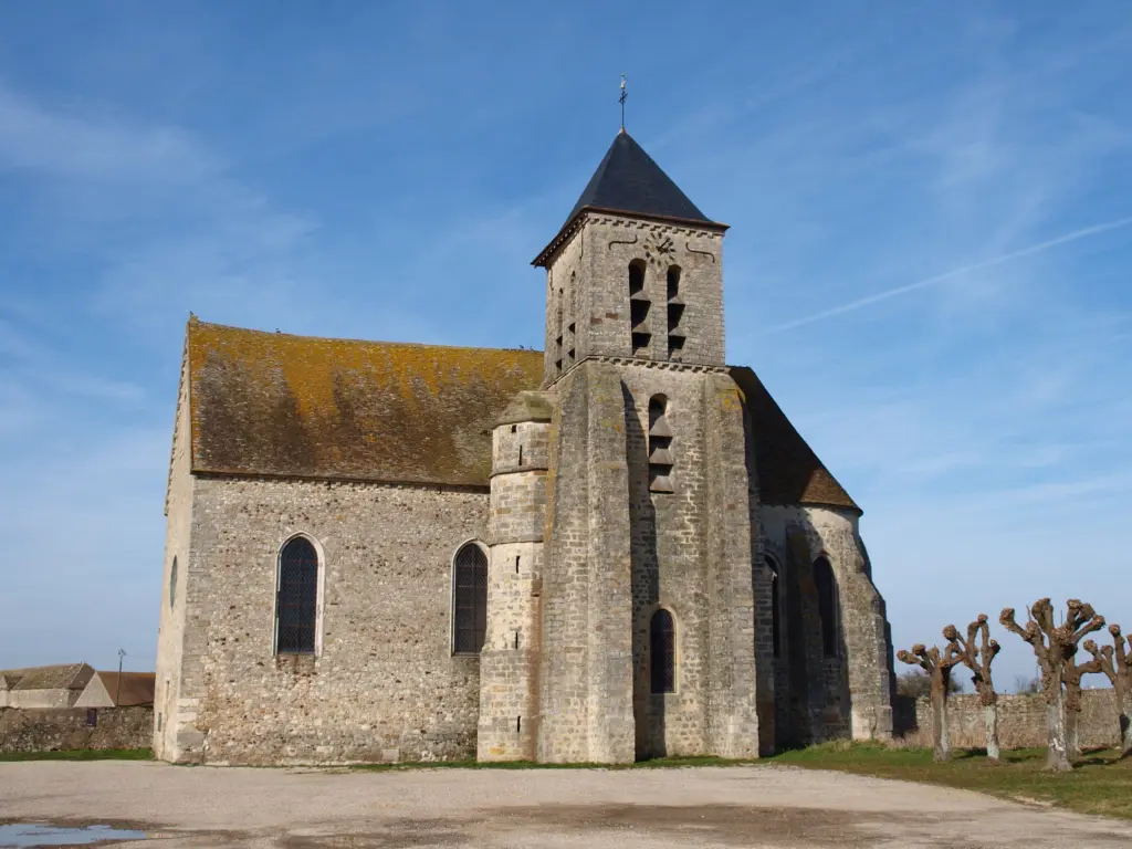 L’église d’Esmans, clocher carré de pierre et toit de tuiles, sous un ciel bleu.