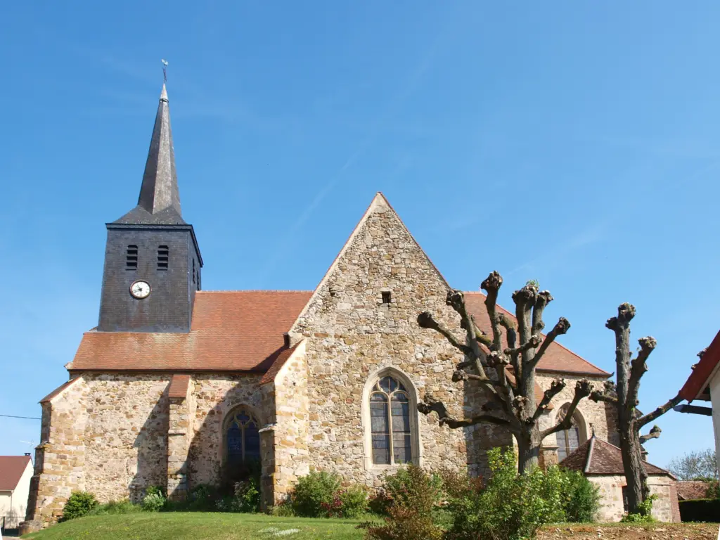 L’église de La Louptière-Thénard, clocher d’ardoise effilé derrière des arbres taillés.