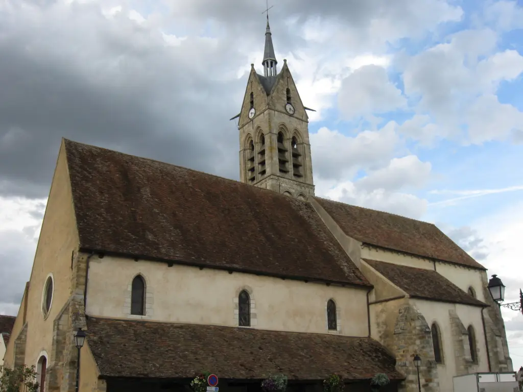 Le Châtelet-en-Brie : l’église, longue nef de pierre et clocher ajouré, sous un ciel nuageux.