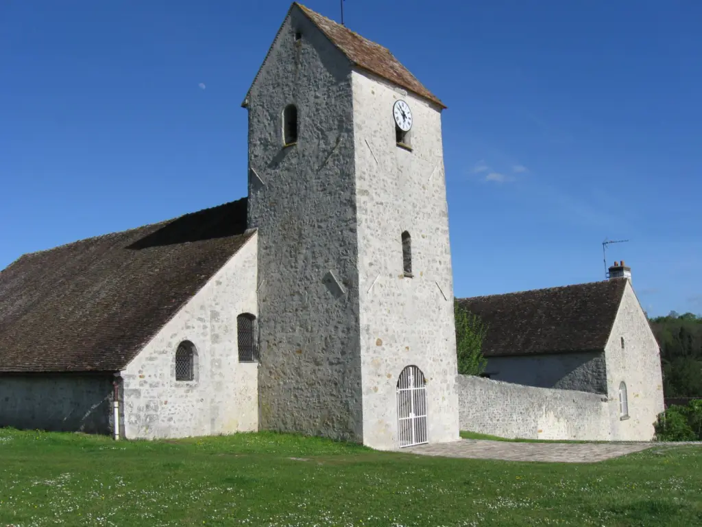L’église de Poligny, tour carrée de pierre et nef basse, sous un ciel bleu.