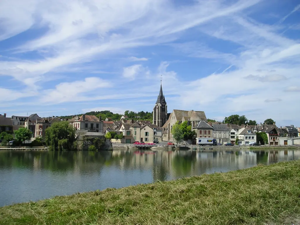 Pont-sur-Yonne vue de l’autre rive : les maisons du bord de l’Yonne et le clocher de l’église, reflétés dans l’eau.