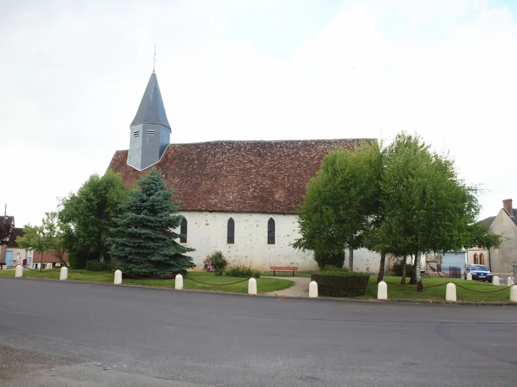 Saint-Martin-d'Ordon : l’église au clocher pointu derrière les sapins de la place.