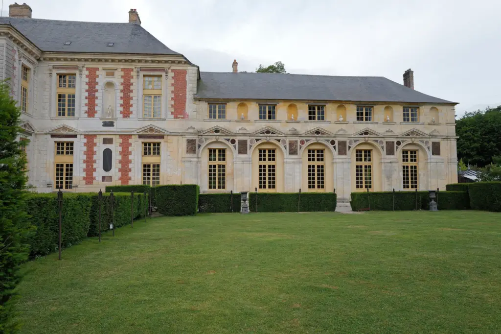 Le château de Vallery, façade de brique et de pierre devant sa pelouse.