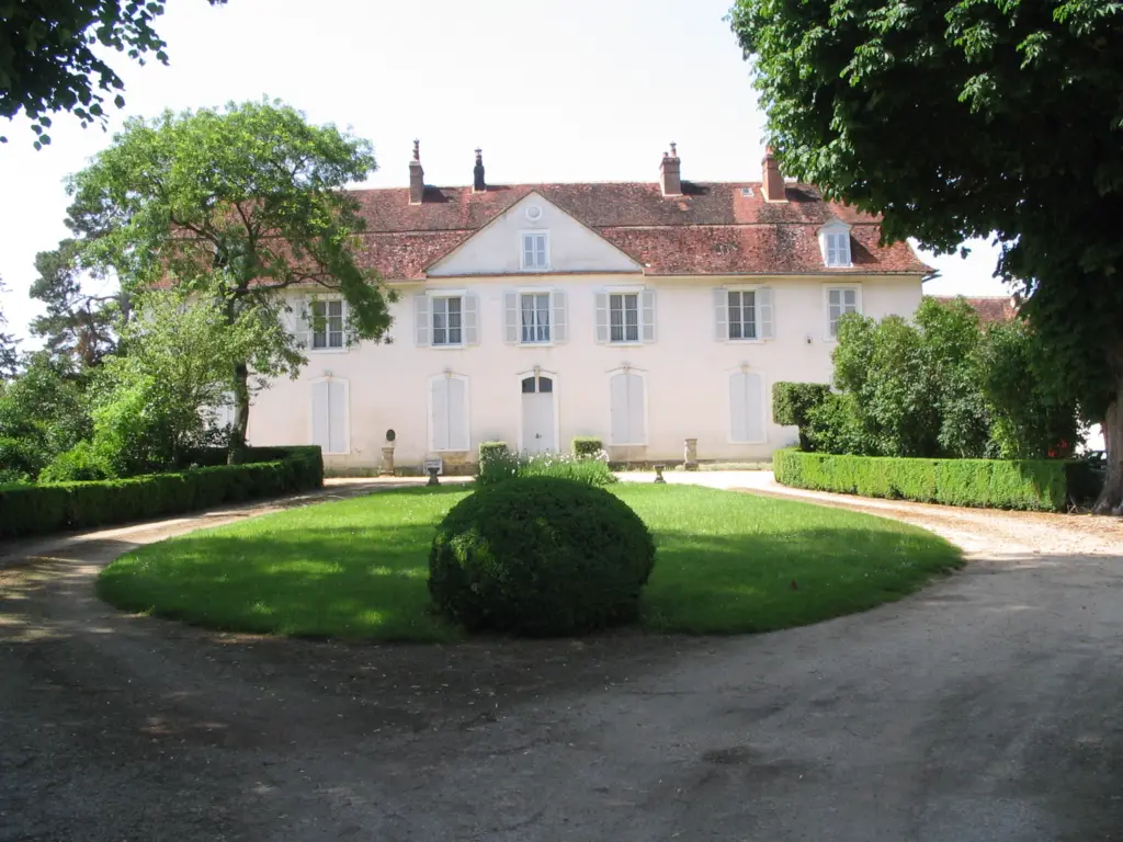 Le château de Vergigny, longue façade claire au bout de sa pelouse ronde.