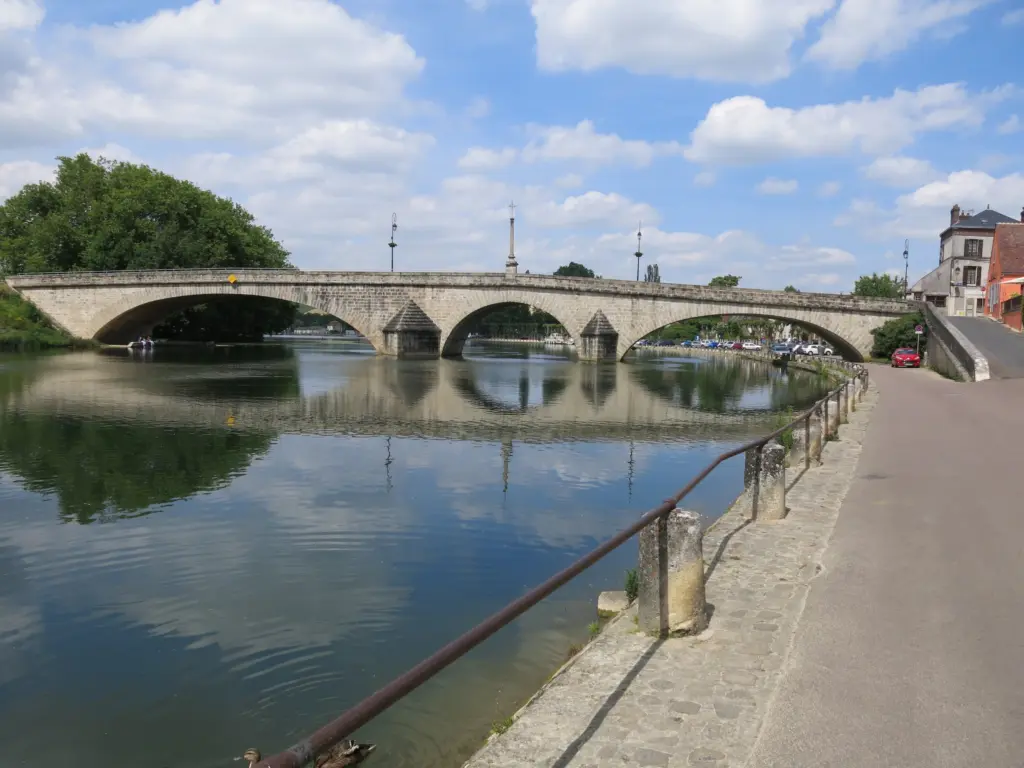 Le pont Saint-Nicolas sur l’Yonne à Villeneuve-sur-Yonne, ses arches de pierre reflétées dans l’eau calme.