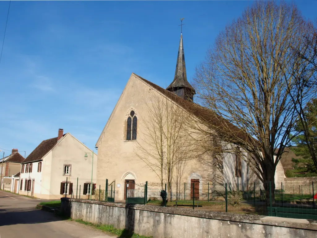 L’église de Villevallier, pignon clair et flèche fine, au bout de la rue.